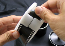 Pull the film leader lightly through the entrance of the reel. Once the film leader is inside the reel, twist the reel in both the clockwise and anticlockwise direction until the film is inside the reel.